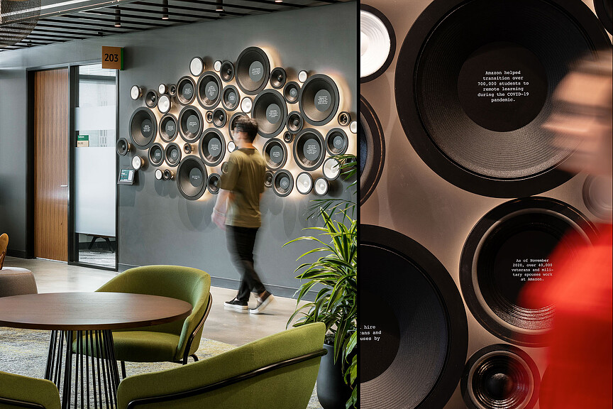 A person walking in a room with a large display of speakers.